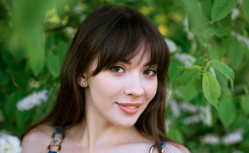 Portrait of a beautiful young woman on the background of a flowering bush