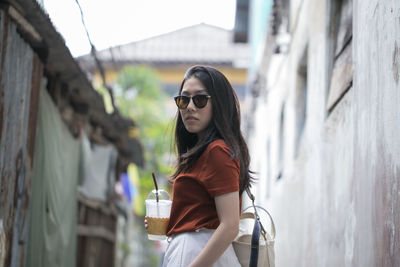Young woman wearing sunglasses while standing in alley