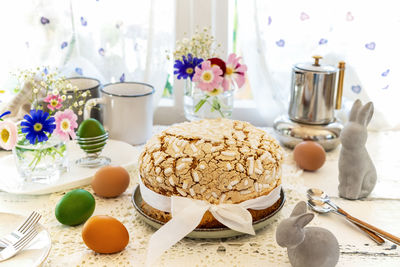 Easter concept with italian easter cake colomba, coloured eggs, spring flowers and rabbits