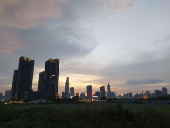 Modern buildings in city against sky during sunset