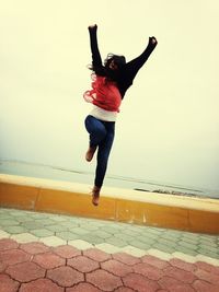 Rear view of young woman jumping in sea