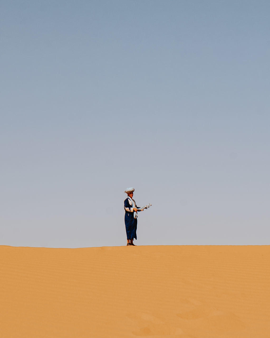 FULL LENGTH OF MAN STANDING ON SAND DUNE