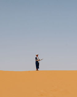 Man standing on sand dune against clear sky