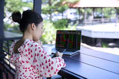 Side view of young woman using laptop at home