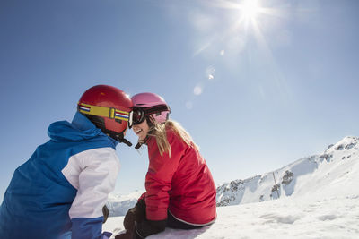 Siblings enjoying on snowcapped mountain against clear sky