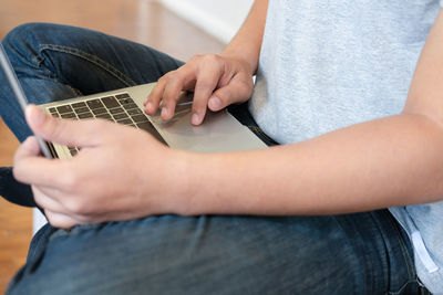 Midsection of man using laptop while sitting indoors