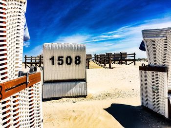 Hooded chairs on beach against buildings