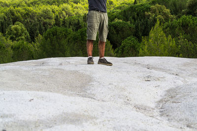 Low section of man standing on rock against trees