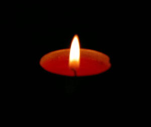 Close-up of illuminated candle over black background