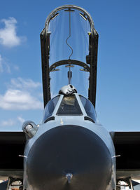 Military fighter jet with open canopy against blue sky