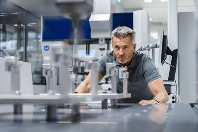 Engineer with gray hair examining machinery in factory