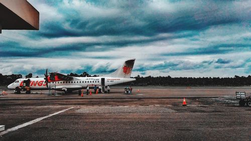 Airplane on airport runway against sky