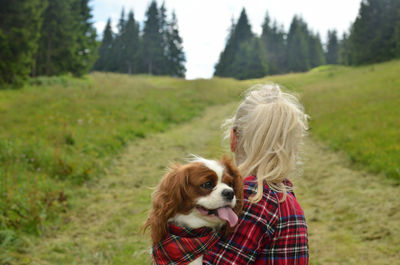 Woman hiking on mountain path with her dog - cavalier king charles spaniel