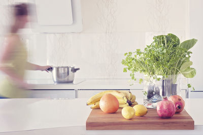 Digital composite image of ghost woman in kitchen at home