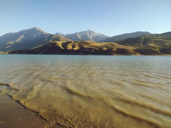 Scenic view of sea and mountains against clear sky