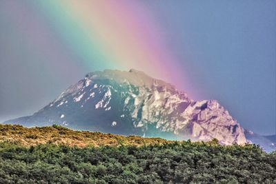 Scenic view of rainbow over mountains against sky