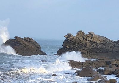 Rock formation in sea against clear sky