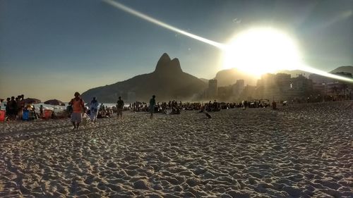 People on beach against sky during sunset