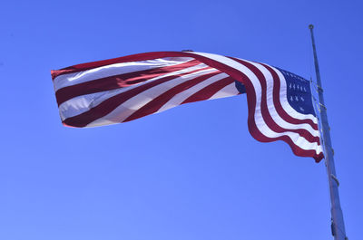 Low angle view of american flag waving against clear blue sky