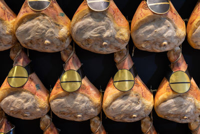 Group of whole raw hams hung on a wall.