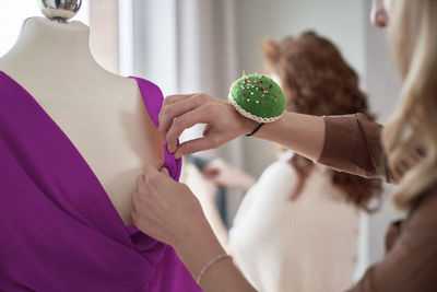 Fashion designer pinning dress on mannequin