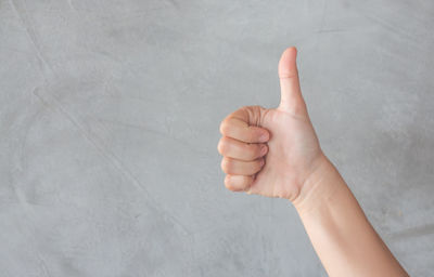 Cropped image of hand gesturing thumbs up sign