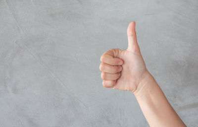 Cropped hand of woman gesturing against wall