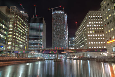 Illuminated bridge over river in city at night