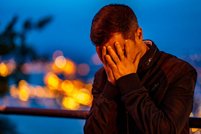 Young man standing against illuminated sky at night