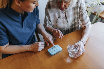 High angle view of female caregiver explaining dose of medicines to senior woman at home