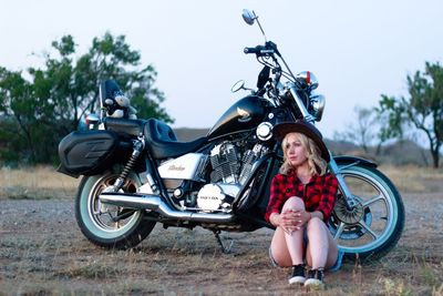 Full length portrait of woman with motorcycle on cart