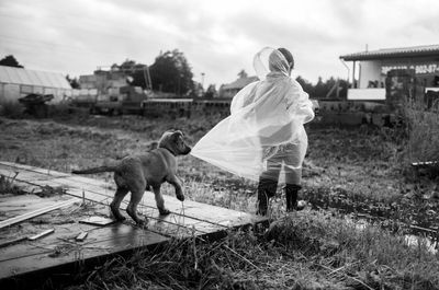  rear view of boy in rain coat and puppy pulling boy back 