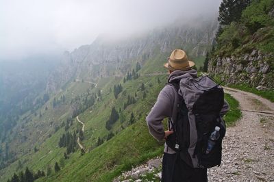 Rear view of man looking at mountains during foggy weather