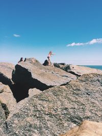 Low angle view of girls on rock formations against sea