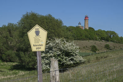 Information sign by lighthouse against sky