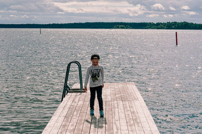 Boy standing in sea against sky