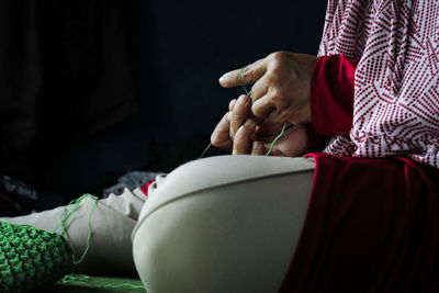 Midsection of woman holding red while sitting at home