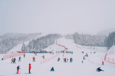 People on snow covered landscape against clear sky