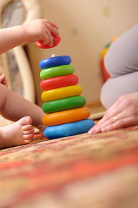 Cropped image of baby playing with toy on floor