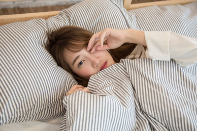 Portrait of young woman lying on bed