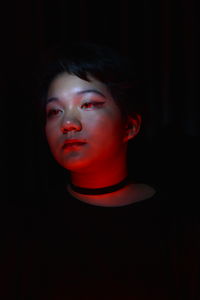 Low lit portrait of a young girl with colored light as accent