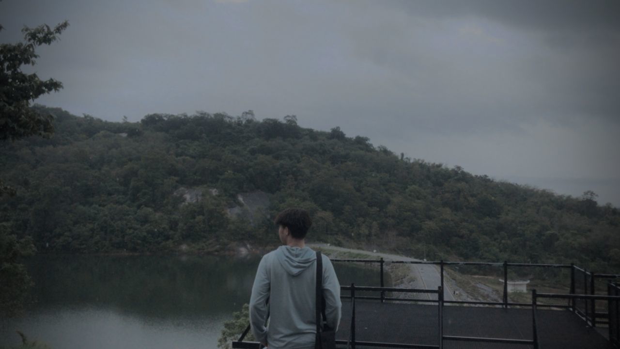 REAR VIEW OF WOMAN STANDING BY RAILING AGAINST LAKE