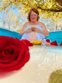 Portrait of woman holding red rose in a milk bath for pregnancy photo