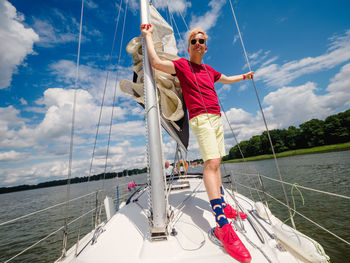 Handsome young person wear standing on a sailboat bow and looking at front in summer day