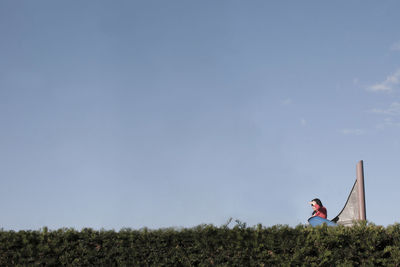 Side view of woman on landscape against blue sky