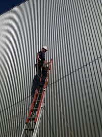 Low angle view of male worker on ladder by building