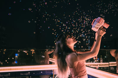 Rear view of woman holding sparkler at night