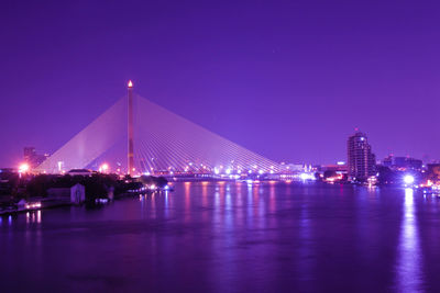 Illuminated bridge over river at night