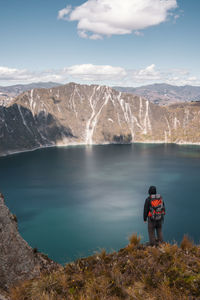 Rear view of man standing on mountain against sky