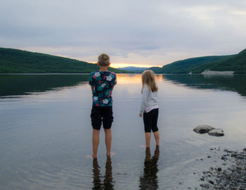 Rear view of women standing in water against sky